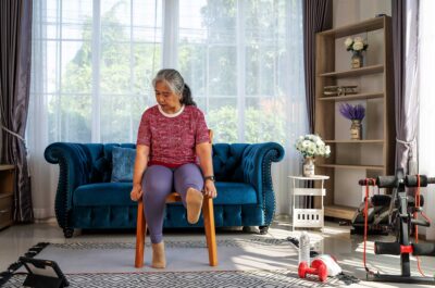 older women seated in a chair exercising at home