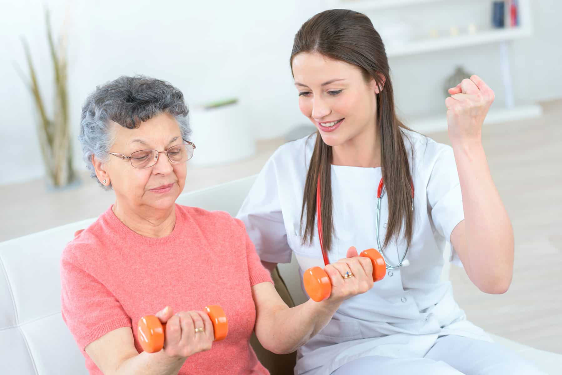 A young women helping an older women exercise with hand weights