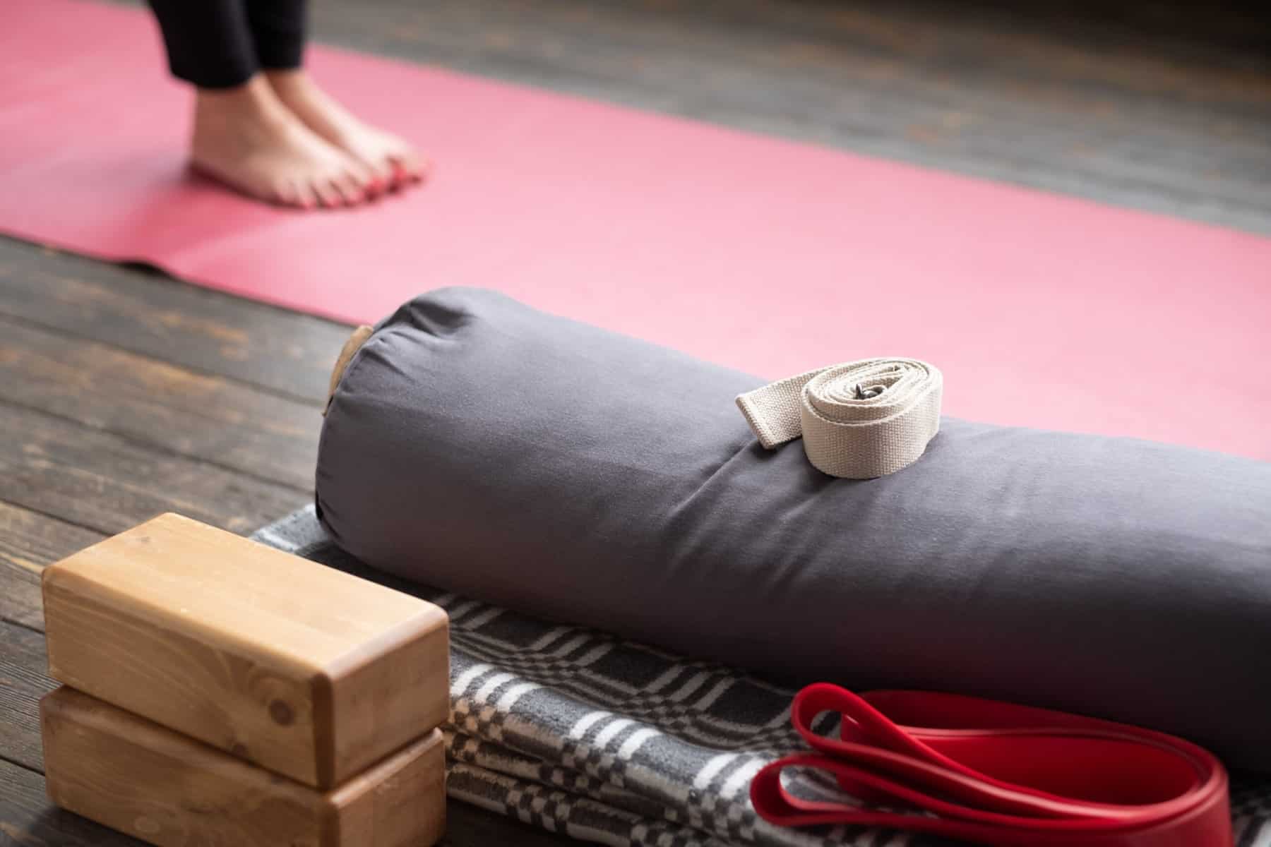 A women's feet on a yoga mat with yoga props including blocks, straps and boltr