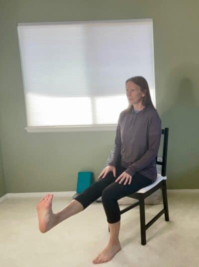 A women seated in a chair with one leg extended and flexing her foot