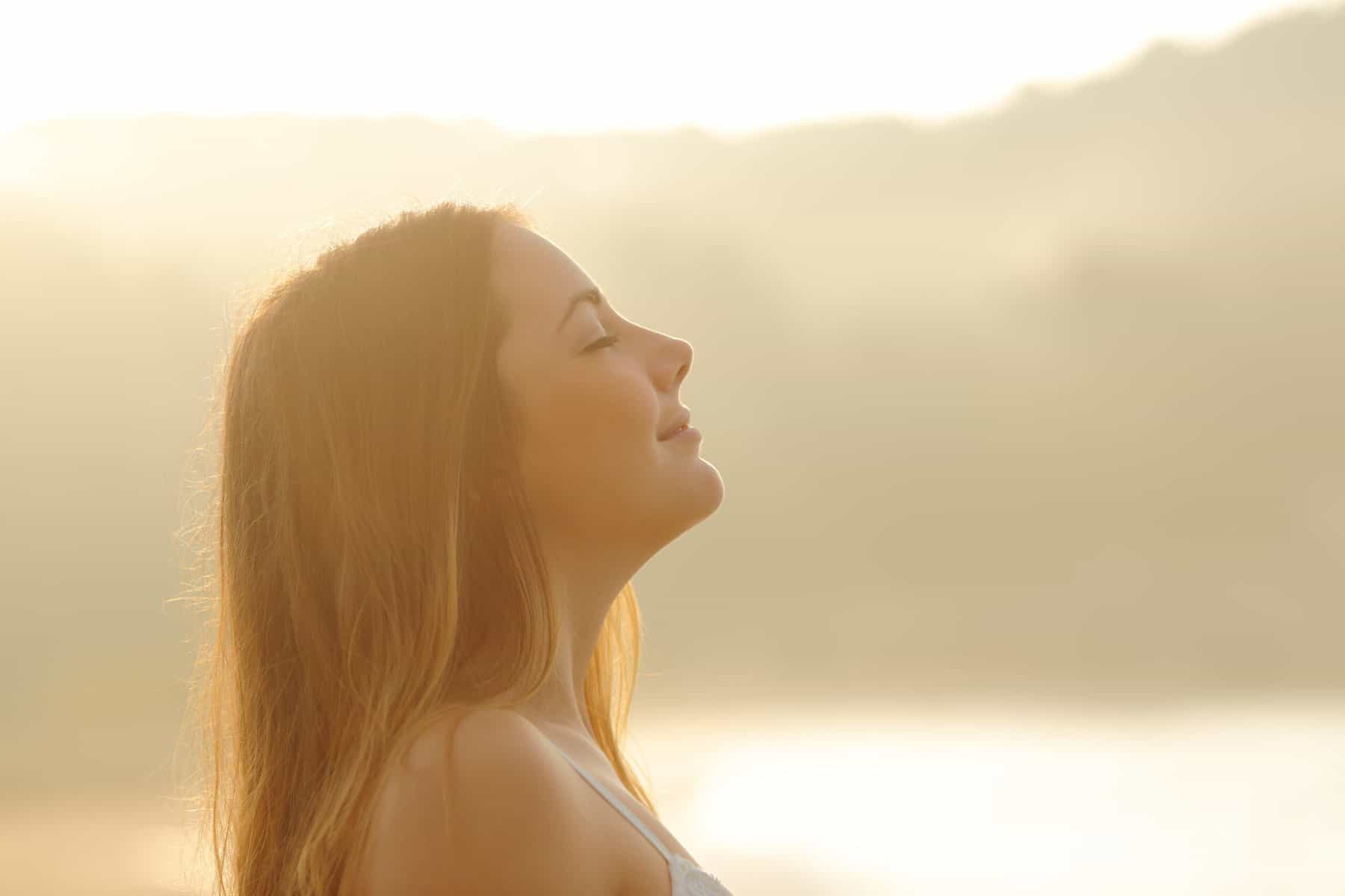 A women taking a deep breath with a calm outdoor background