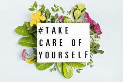 A lightbox that says- #take care of yourself on top of flowers