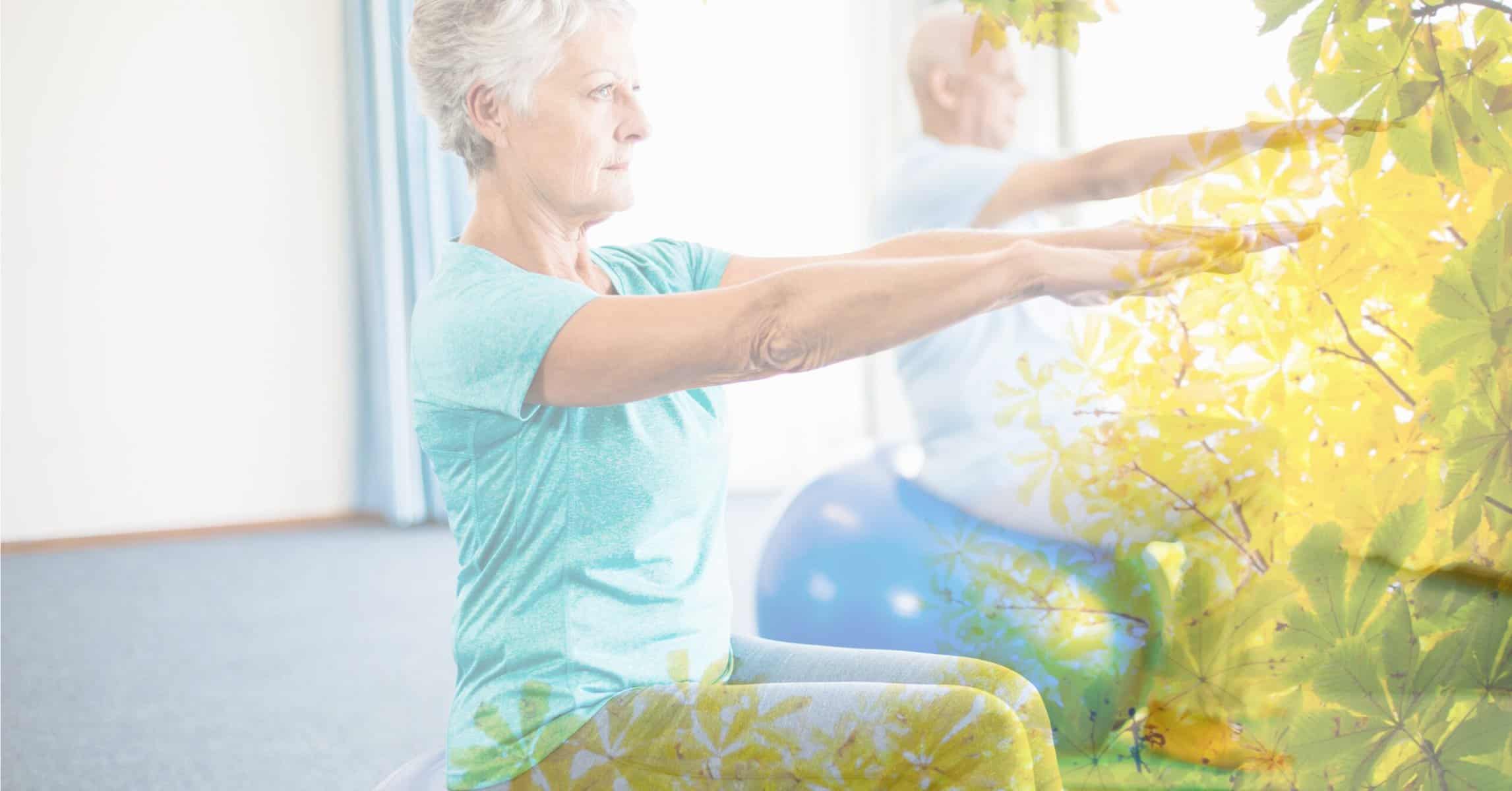 An older man and an older woman seated on an exercise ball with their arms raised for a seated exercise.