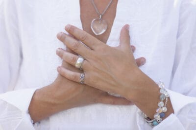 A cropped image of a woman's hands together at her heart center as she practices a centering meditation.