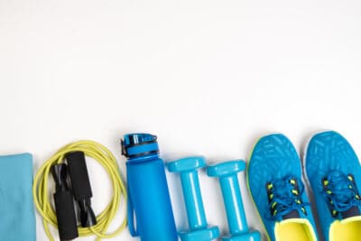 Exercise equipment for seniors including light hand weights, resistance bands, water bottle, and sneakers.