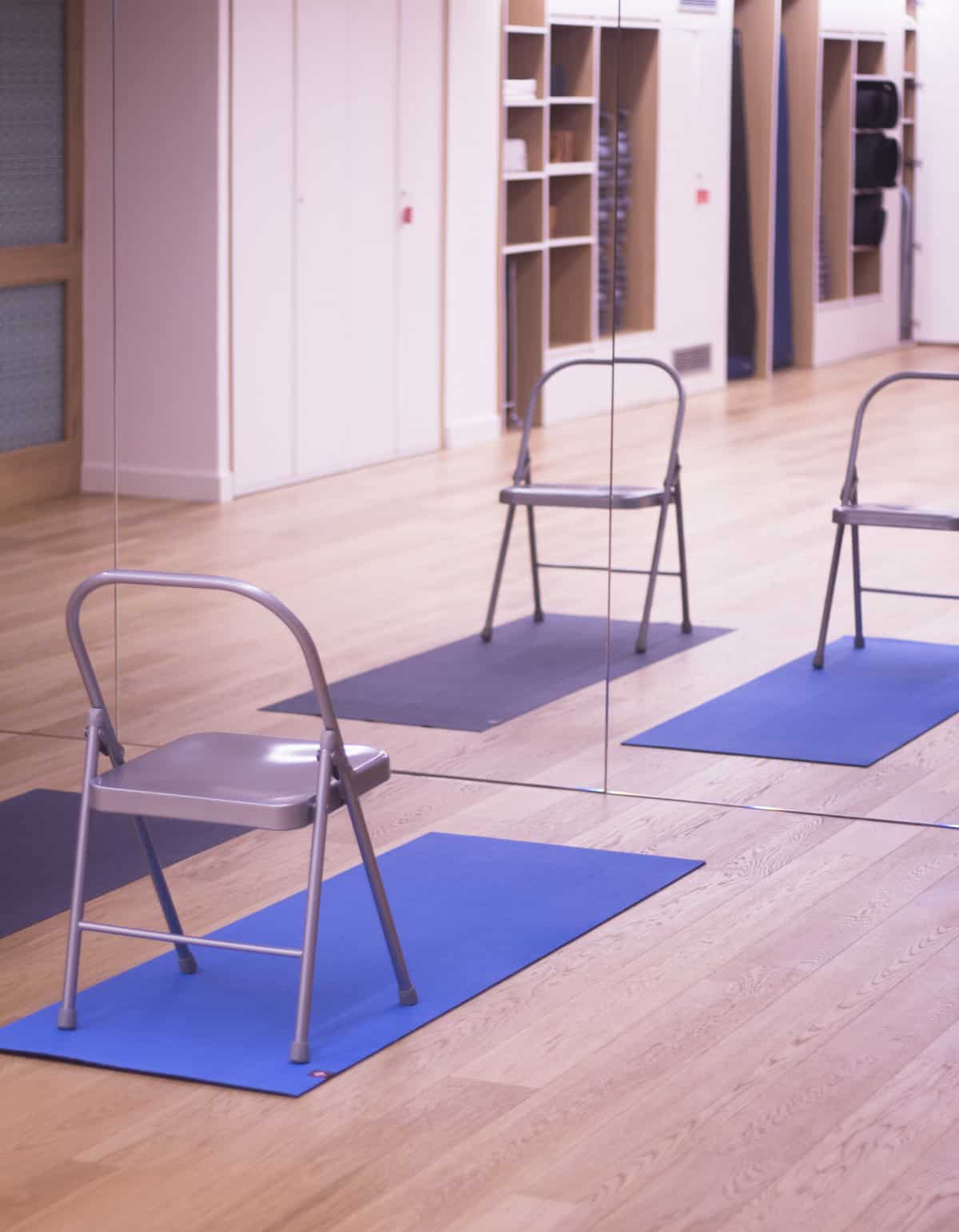 A cropped image of three chairs on yoga mats in preparation for a chair yoga class,