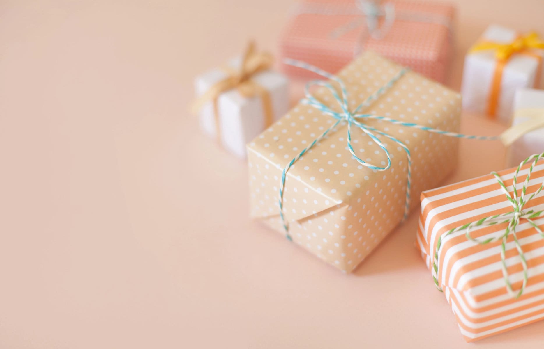 A cropped image of pastel wrapped gift boxes on a pink background.